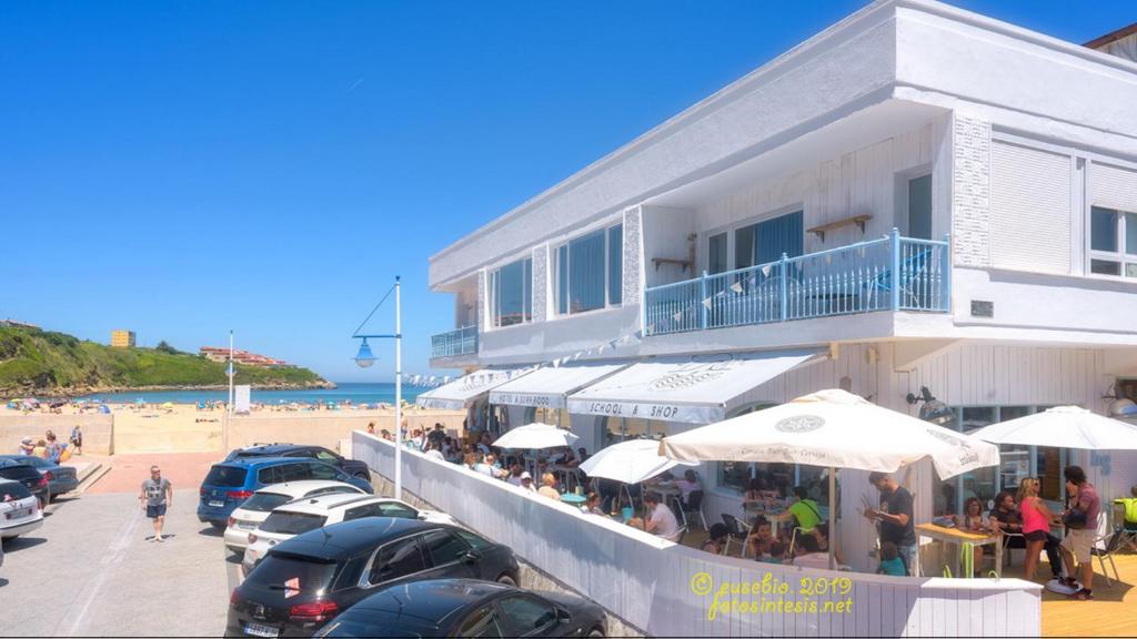 苏安塞斯La Surfería Suances的大楼旁的海滩上的餐厅