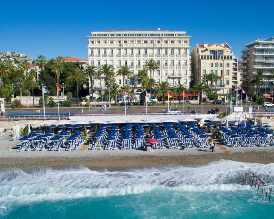 尼斯西区漫步酒店 的海滩上设有蓝色椅子,建筑