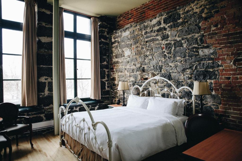 蒙特利尔Auberge du Vieux Port by Gray Collection的卧室设有砖墙和白色的床