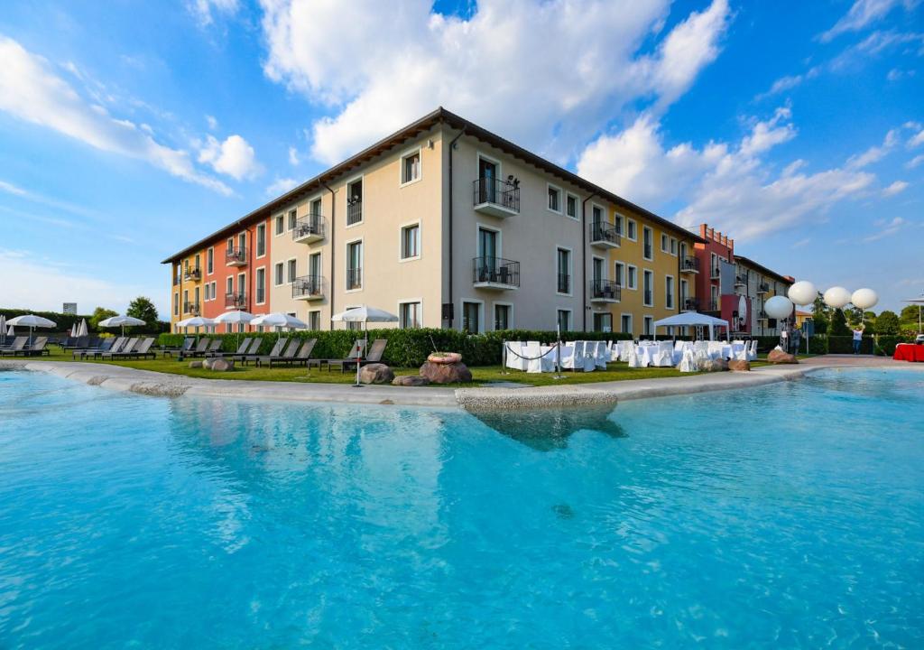 拉齐塞TH Lazise - Hotel Parchi Del Garda的建筑前有蓝色水的建筑