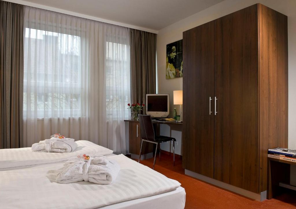 萨尔茨堡PLAZA INN Salzburg City的酒店客房设有两张床和一张带电脑的书桌