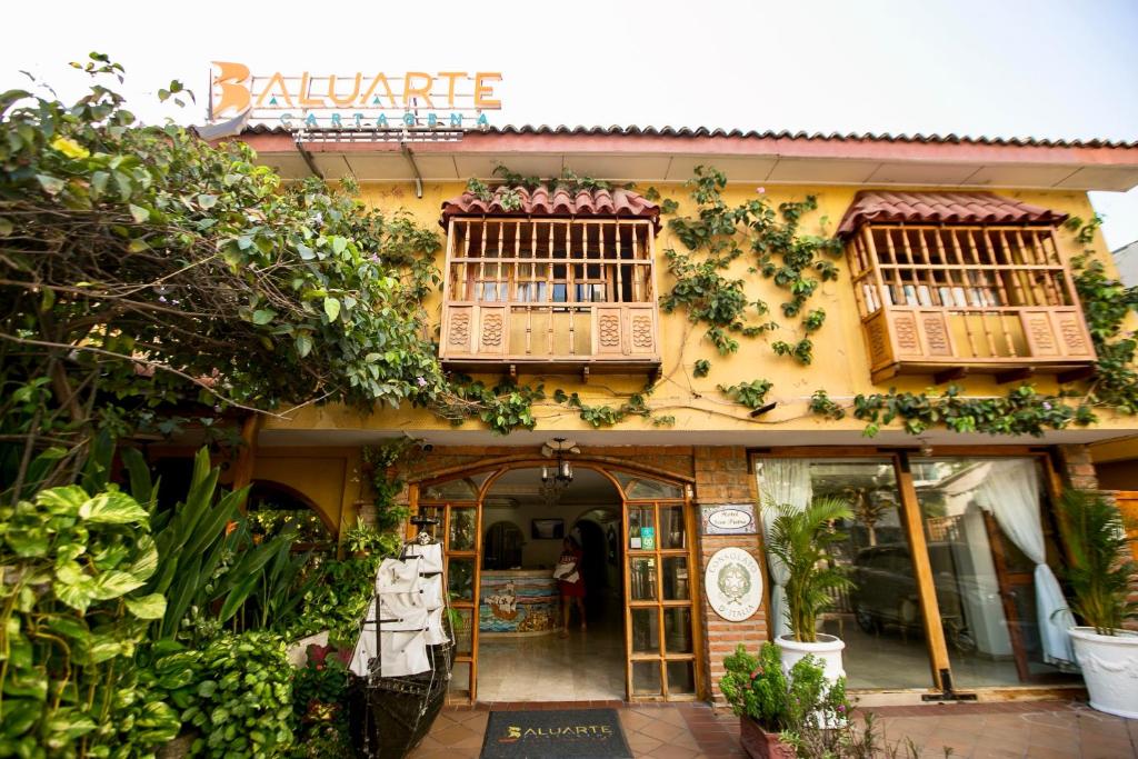 卡塔赫纳Baluarte Cartagena Hotel Boutique的一座黄色的建筑,里面装有窗户和植物