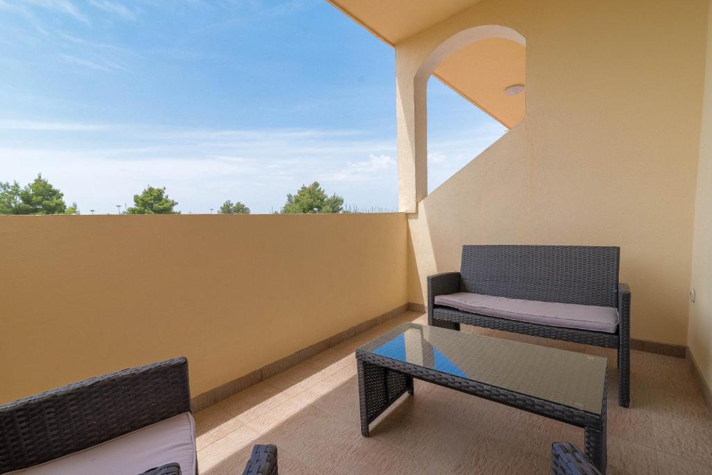 苏科尚Apartman Burčul的阳台配有椅子和玻璃桌
