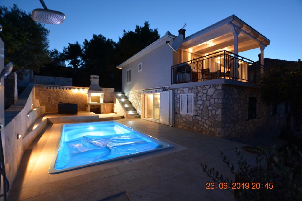 罗加克Sealodge - Luxe Villa, private pool, mooring, parking, sea & mountain view, at 150 m from idyllic private beach的夜间在房子前面的游泳池