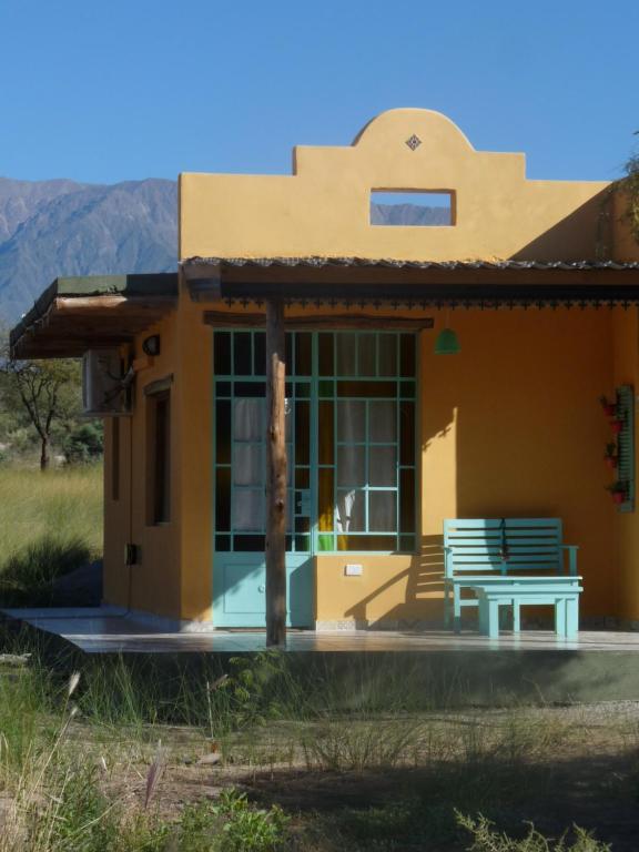 贝伦Los Remenizos Cabañas de Montaña的前面有长凳的小黄色房子