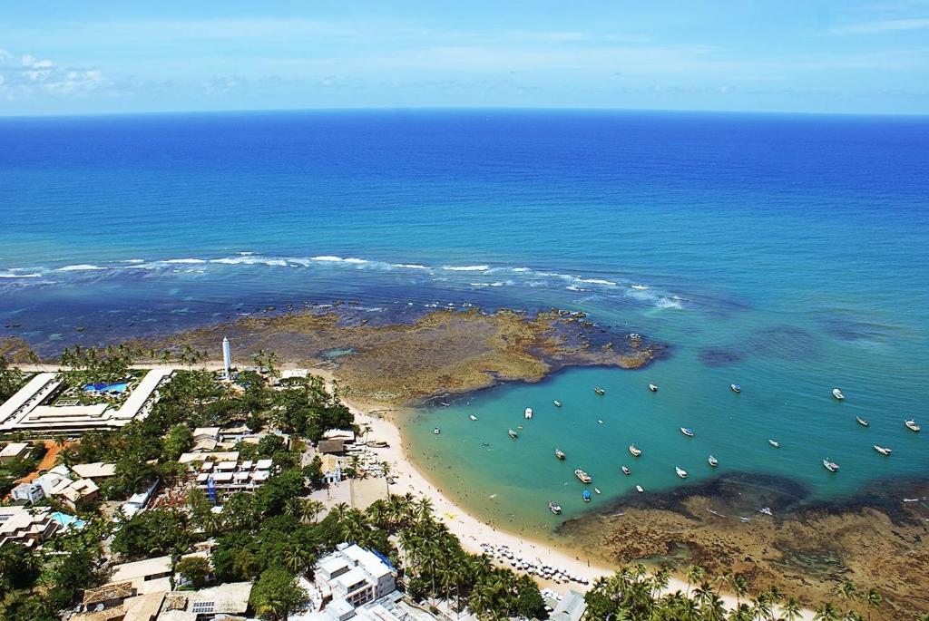 普拉亚多Praia do Forte Suites的享有海滩的空中景色,在水中划船