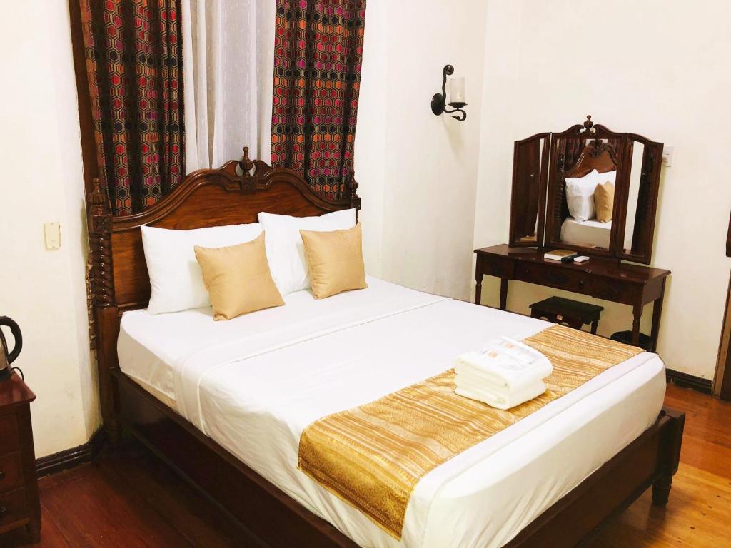 美岸My Vigan Home Hotel的一间卧室配有一张带木制床头板和镜子的床