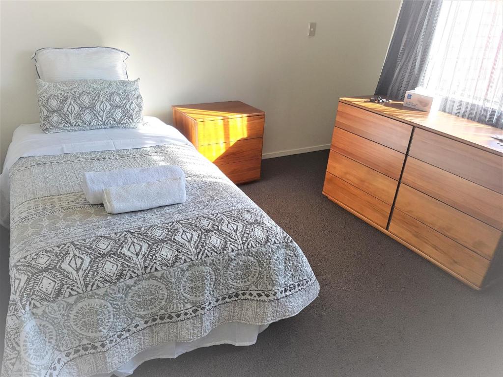 奥克兰Sylvia Park House的一间卧室配有一张床和一个木制梳妆台