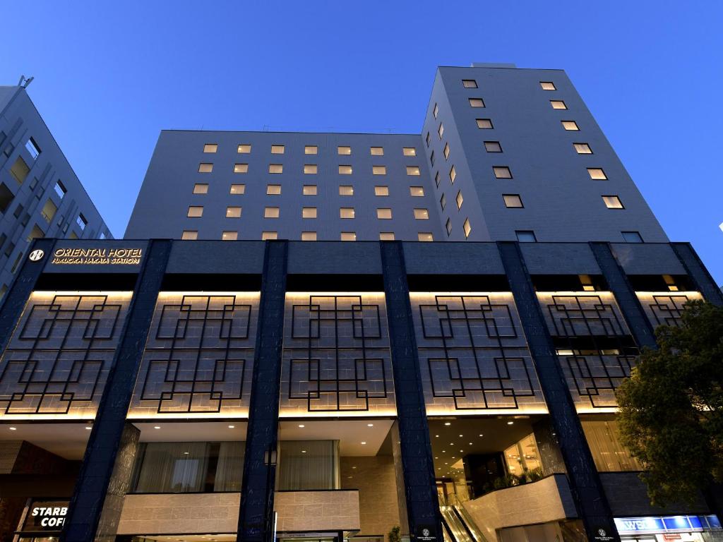 福冈Oriental Hotel Fukuoka Hakata Station的一座高大的黑色建筑,两座高大的建筑