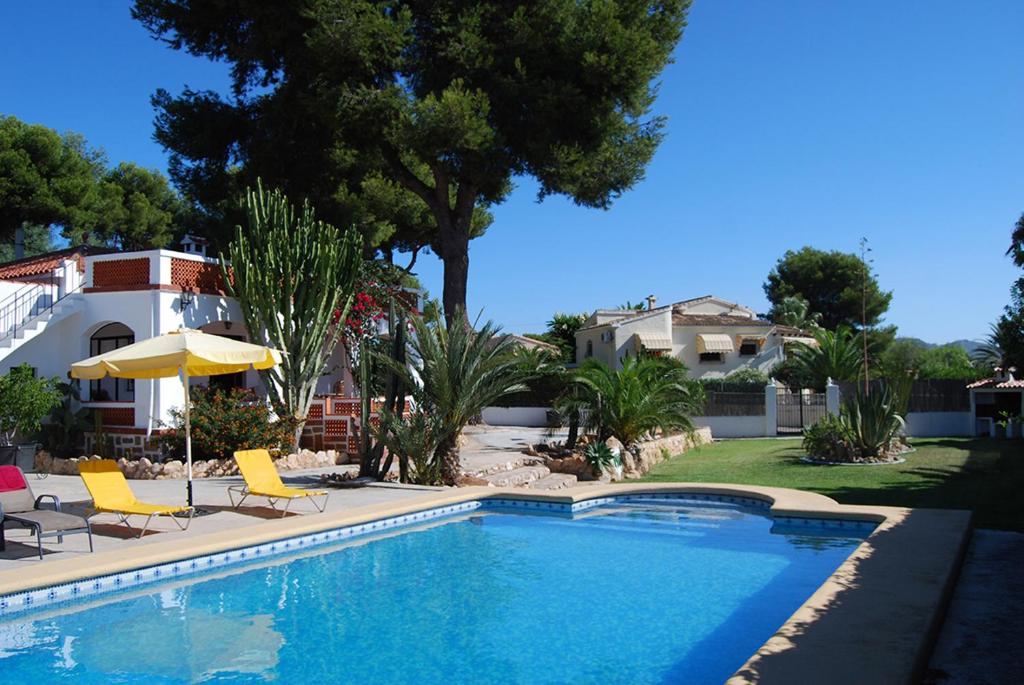 莫莱拉Villa Maria Beach Villa的一个带椅子和遮阳伞的游泳池以及一间房屋