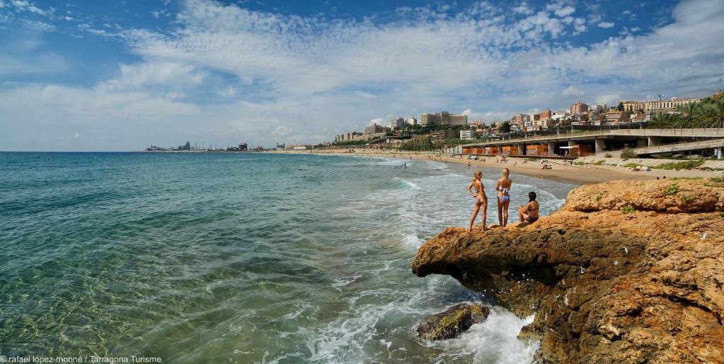 塔拉戈纳Tarragona Ciudad, El Serrallo AP-3的一群人站在海滩的岩石上
