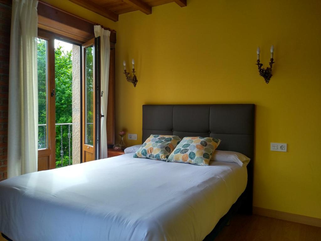 坎加斯-德奥尼斯Casa de Aldea La Xunta的一间卧室设有一张大床、黄色的墙壁和窗户