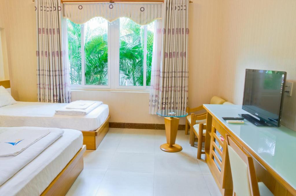Tuy PhongMui Tau Hotel Phan Ri Cua的客房设有两张床、一张桌子和一个窗户。