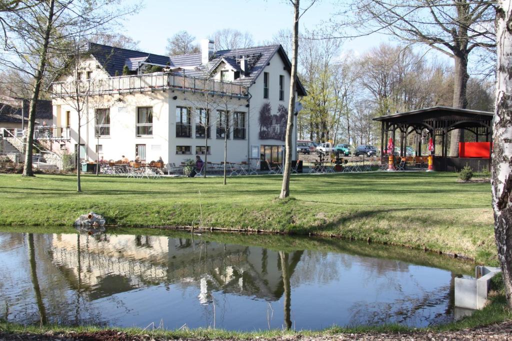 PeitzPension-Maustmühle的一座白色的大房子,前面有一个池塘