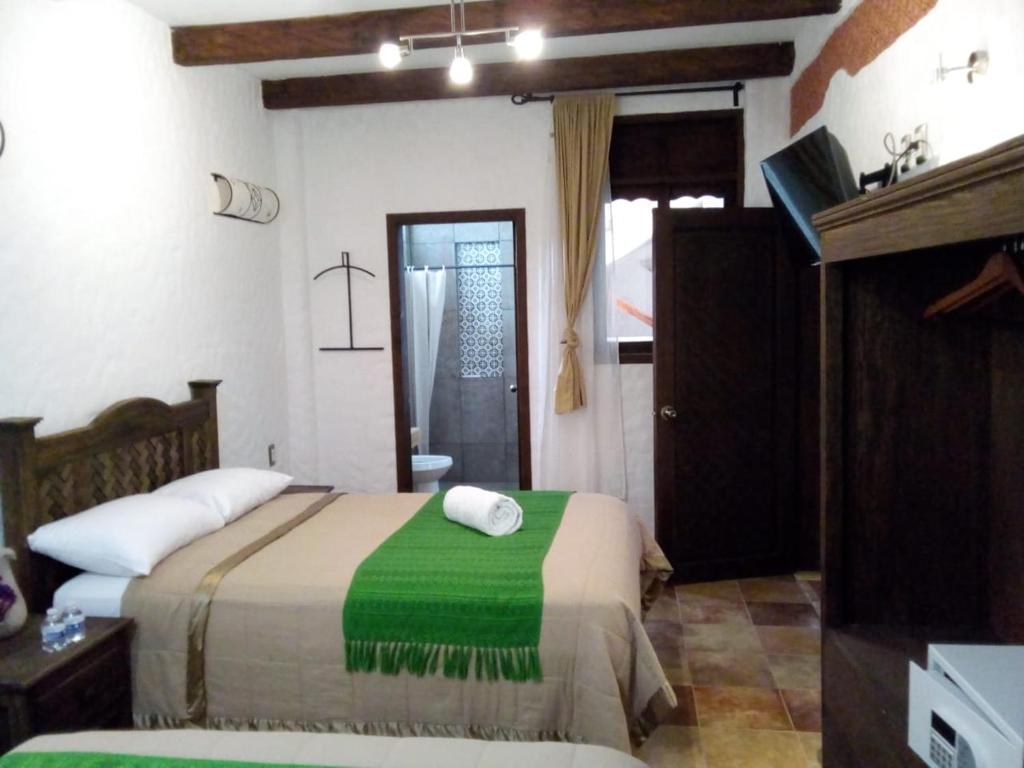 圣克里斯托瓦尔-德拉斯卡萨斯Hotel Na´Lum的一间卧室配有一张带绿毯的床