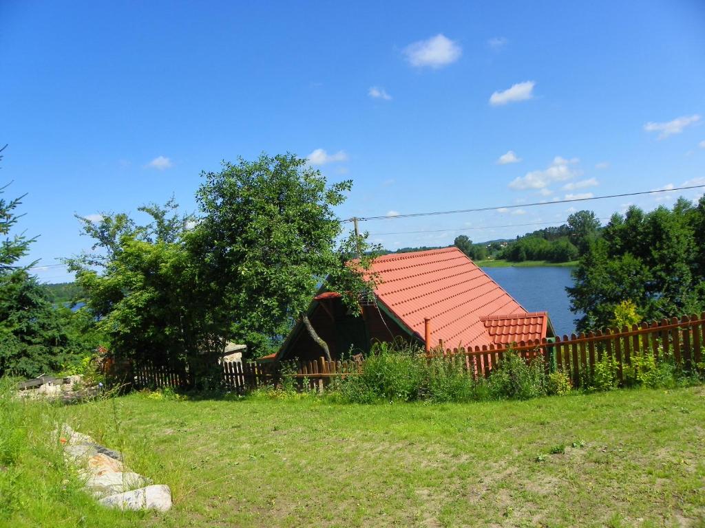 HartowiecDom Letniskowy Ostaszewo的围栏旁有红色屋顶的房子