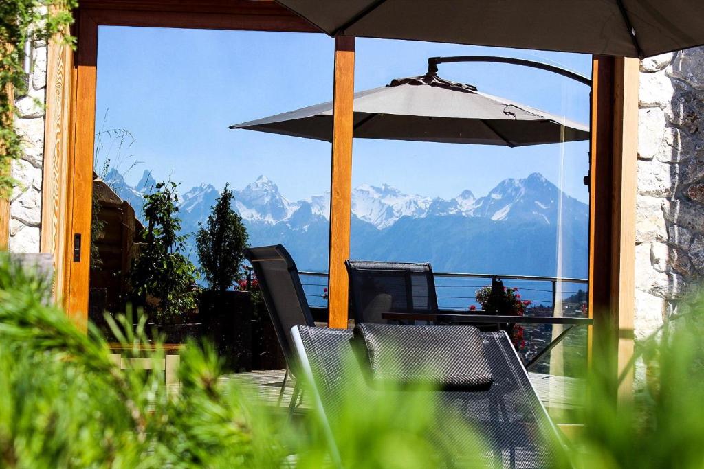 韦松纳Appartement supérieur Winoka Lodge的一个带桌子和雨伞的庭院和山脉