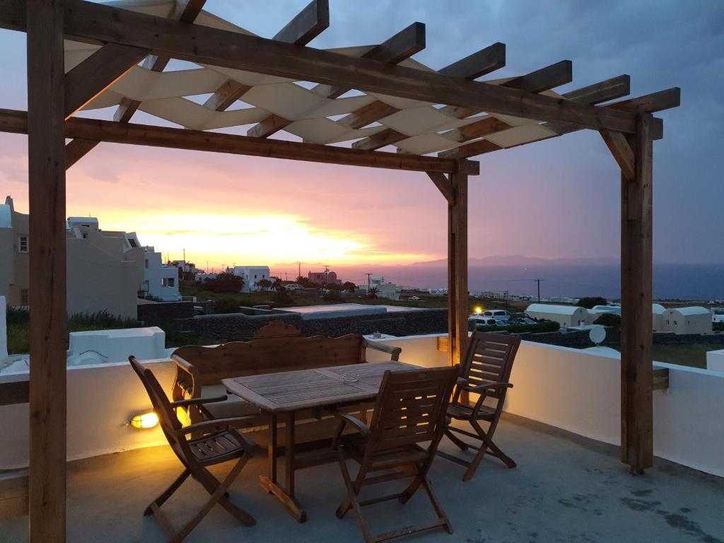 伊亚伊桑公寓及别墅 的阳台上的木桌和椅子,享有日落美景