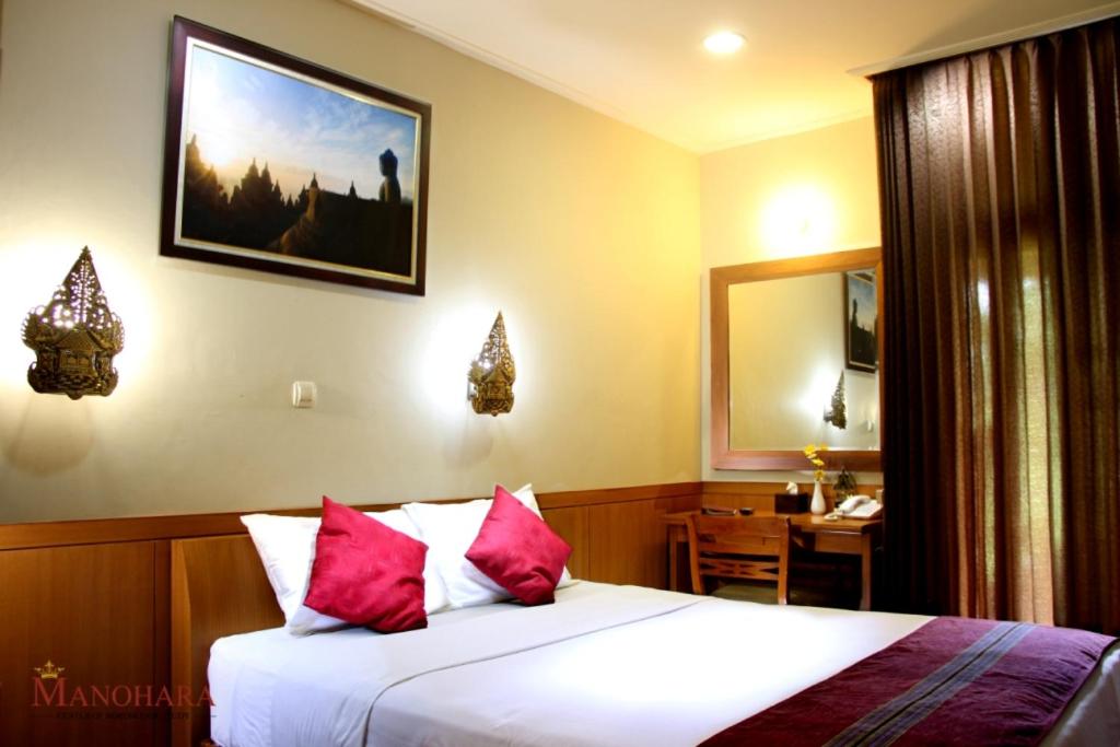 婆罗浮屠曼诺哈拉假日酒店的一间卧室配有一张带红色枕头的床和一张书桌