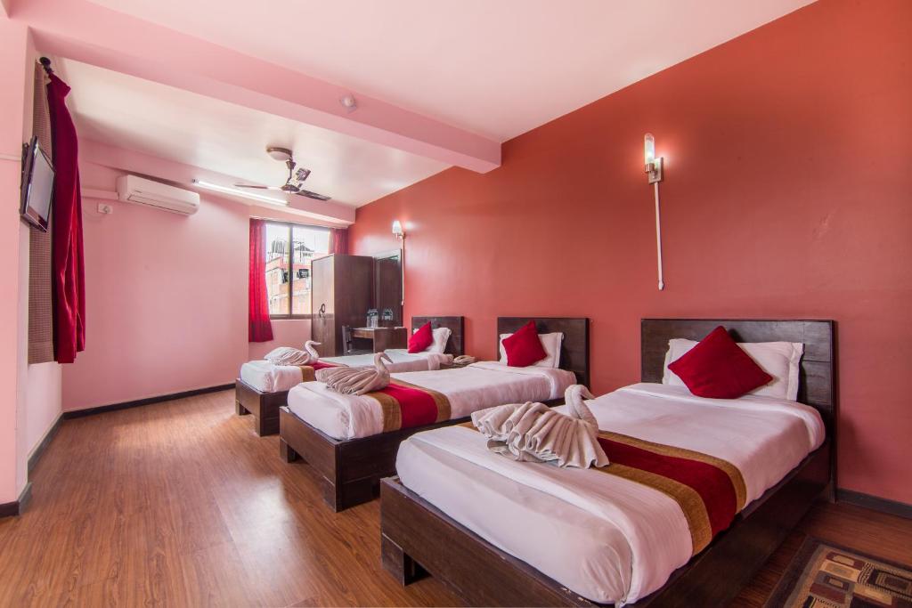 加德满都家庭住宅酒店的红色墙壁的房间里设有三张床