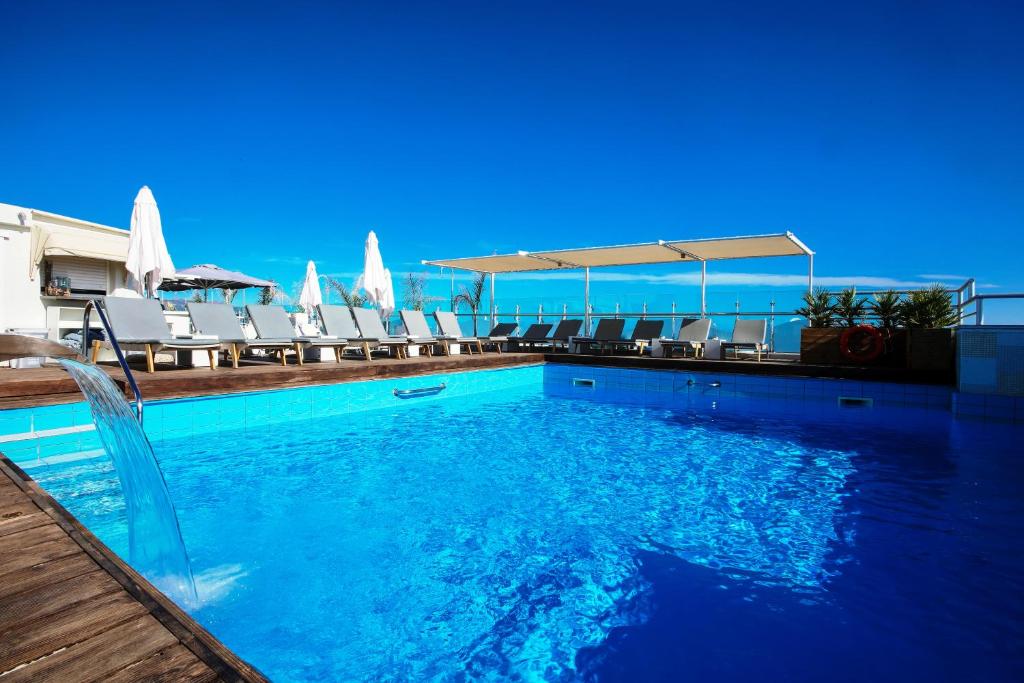 海若克利欧卡普西斯道夫伊拉克利翁酒店的一个带椅子的游泳池,背景是大海