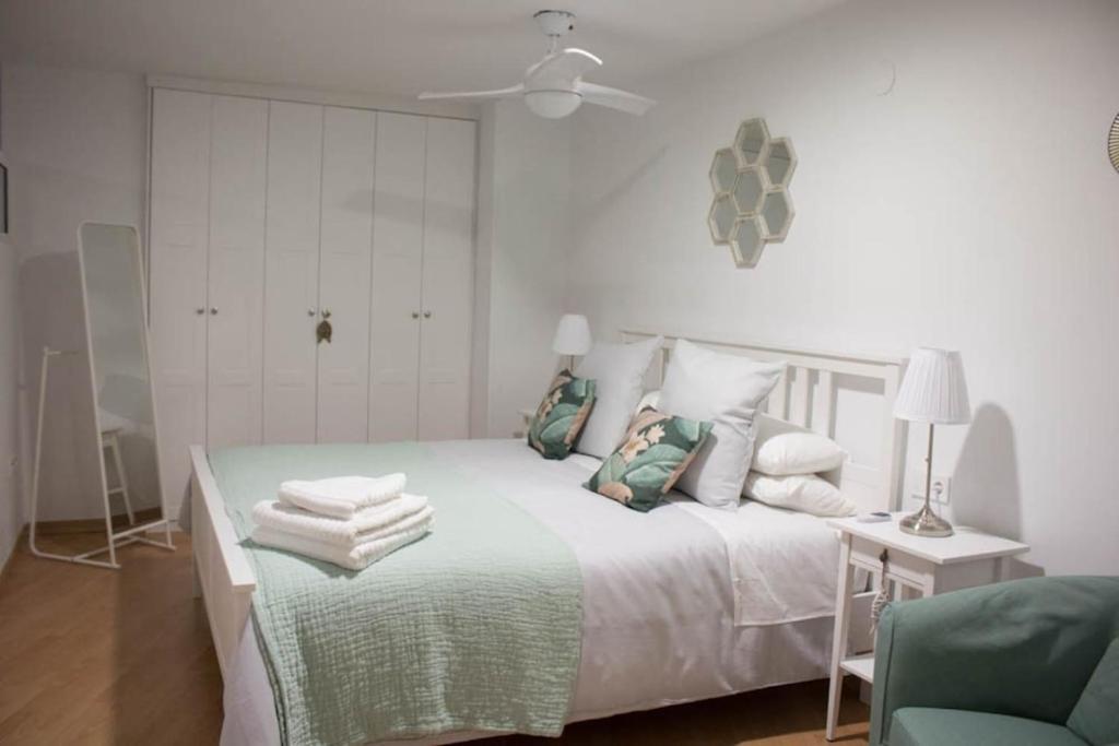 阿尔么丽亚Apartamento Reyes Catolicos的白色卧室,配有床和绿色椅子