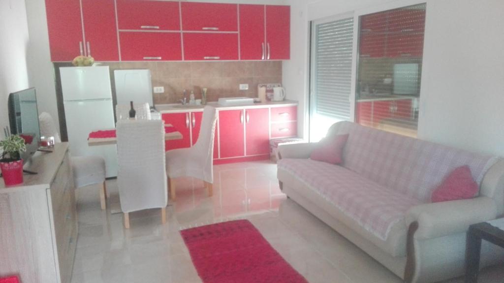 蒂瓦特Apartman Strahinja的带沙发的客厅和带红色橱柜的厨房