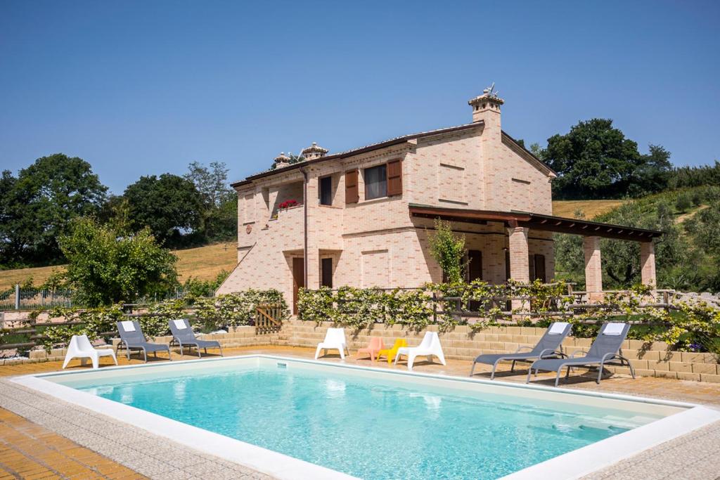 奥西莫Sottocastello Il Casale的一个带椅子的游泳池以及一座房子