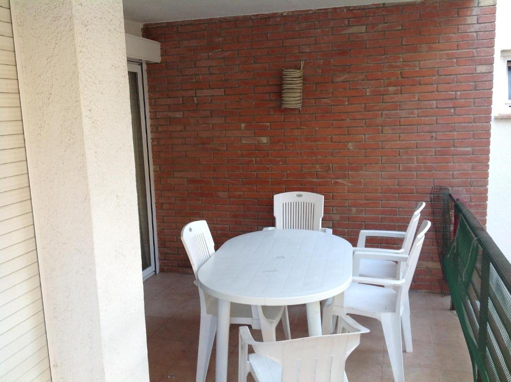 普拉加德阿罗阿罕布拉旅游公寓的一个带砖墙的阳台,配有一张白色的桌子和椅子