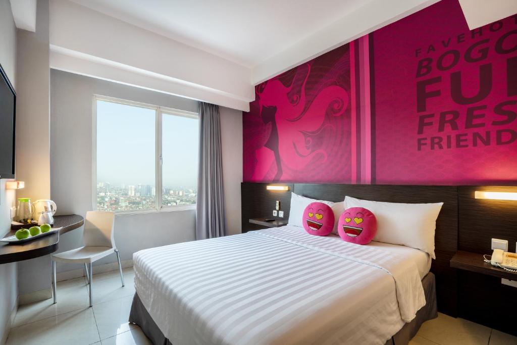 茂物茂物帕德加加兰法维酒店的酒店客房,设有床铺和粉红色的墙壁
