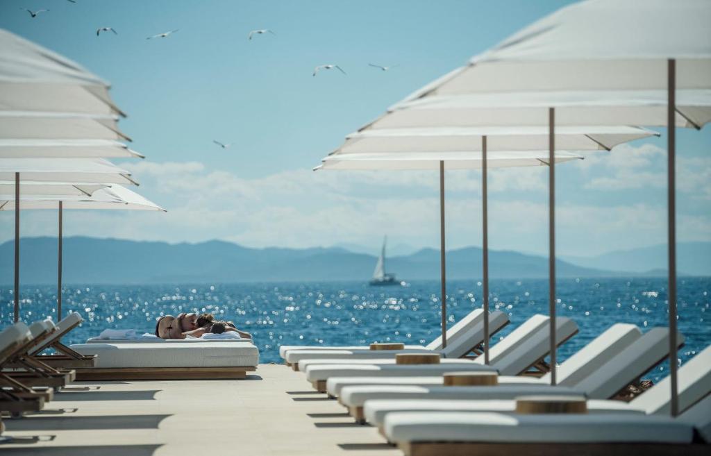雅典Four Seasons Astir Palace Hotel Athens的海滩上的一排躺椅和遮阳伞