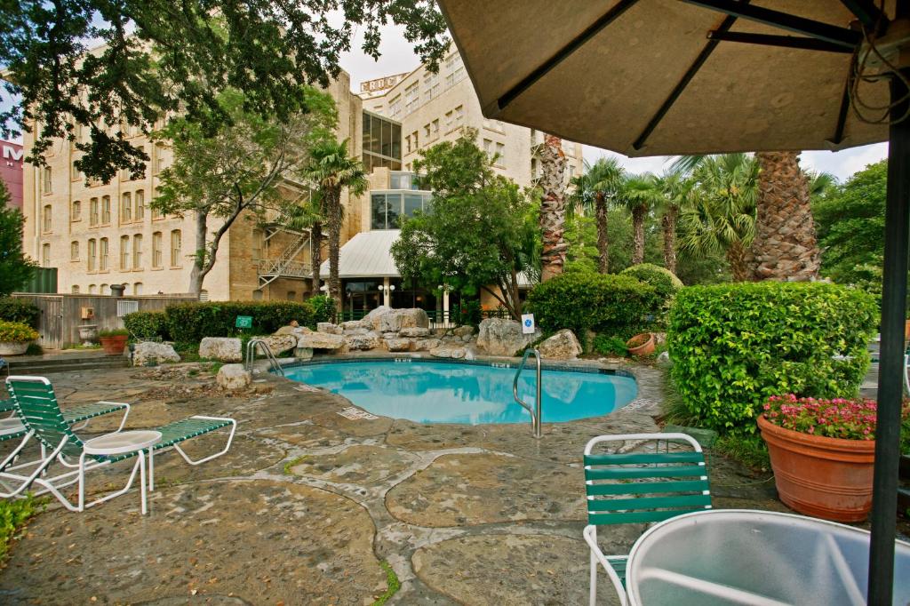 圣安东尼奥克罗基特酒店的一个带椅子和桌子的游泳池以及一把遮阳伞