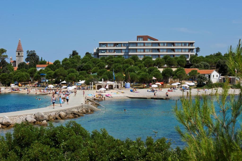 罗维尼Maistra Select All Suite Island Hotel Istra的一片有人居住的海滩和一座建筑