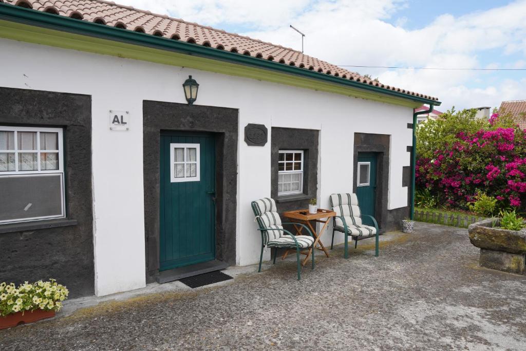 普拉亚达维多利亚Casa do ti' Marrão的一间白色的小房子,设有绿门和两把椅子