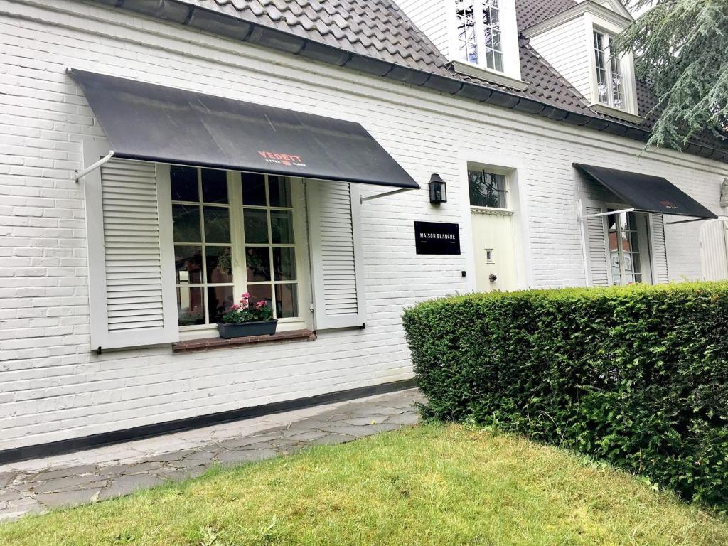 WielsbekeMaison Blanche的白色的房子,有黑色遮阳篷和窗户