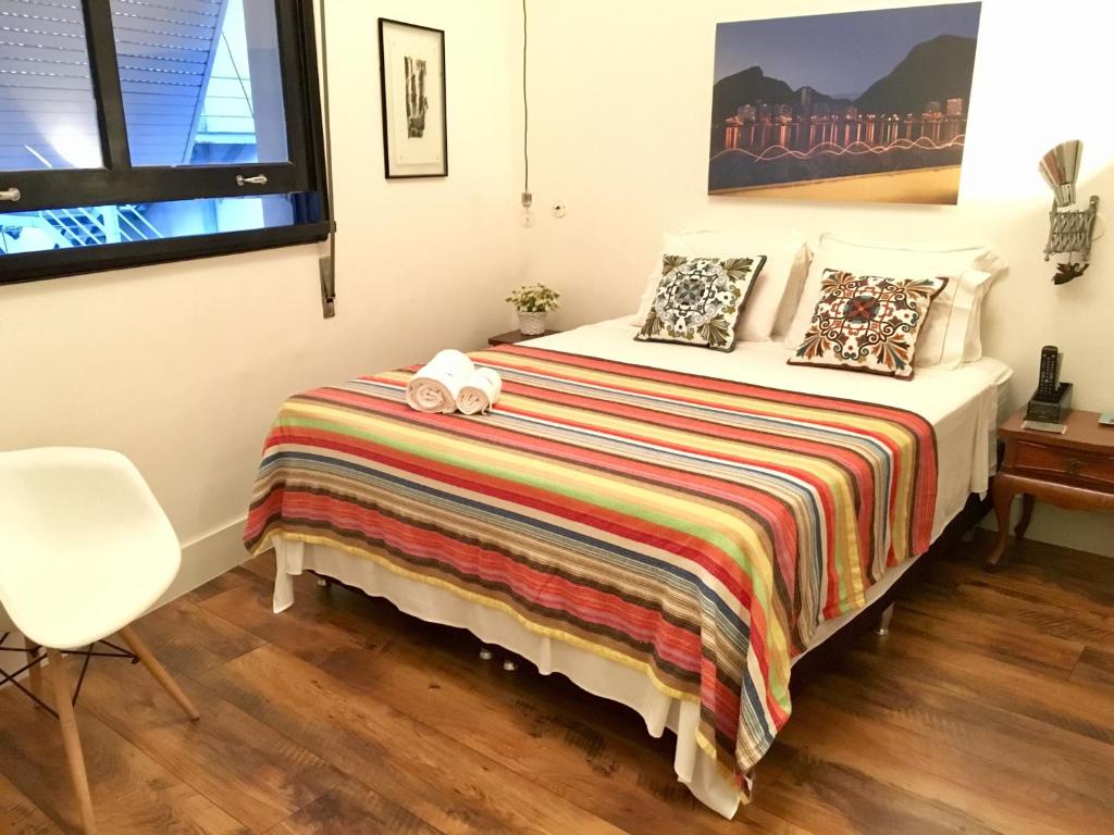 里约热内卢Studio2 Rio Beira Mar的一间卧室配有一张带毯子和椅子的床