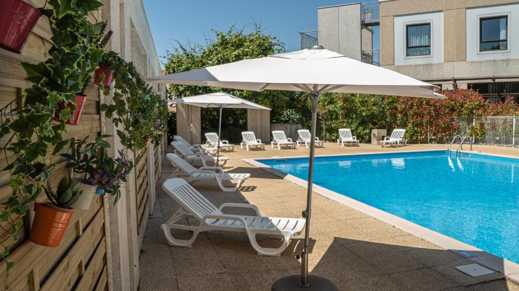 尼奥尔尼奥尔马莱波特温美居酒店的游泳池旁设有躺椅和遮阳伞