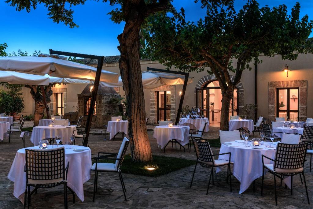 马尔萨拉Hotel Baglio Oneto dei Principi di San Lorenzo - Luxury Wine Resort的户外用餐区配有白色的桌椅