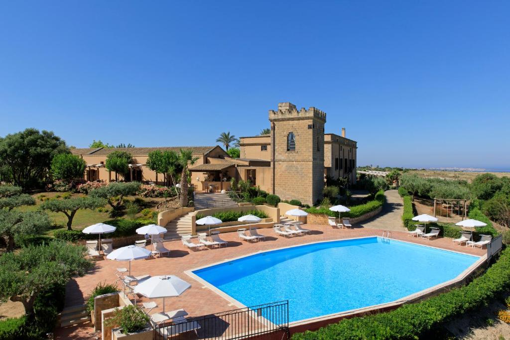 马尔萨拉Hotel Baglio Oneto dei Principi di San Lorenzo - Luxury Wine Resort的一座带遮阳伞的建筑前的游泳池