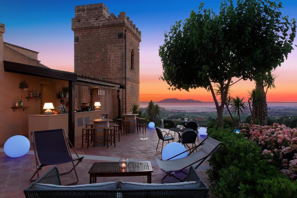 马尔萨拉Hotel Baglio Oneto dei Principi di San Lorenzo - Luxury Wine Resort的庭院配有桌椅,享有日落美景。