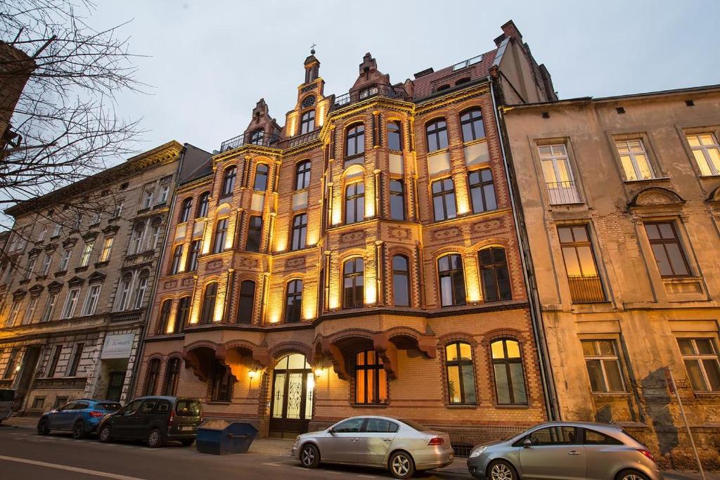 波兹南Loft Apartments Poznań的一座大型建筑,前面有汽车停放