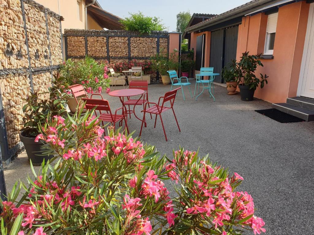 DruillatChambre D´hôtes Léonie & Restaurant的庭院配有桌椅和粉红色的鲜花