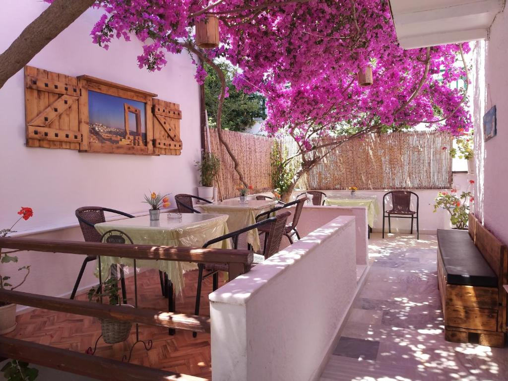 纳克索乔拉Syrianos Hotel的一个带桌椅和紫色鲜花的庭院