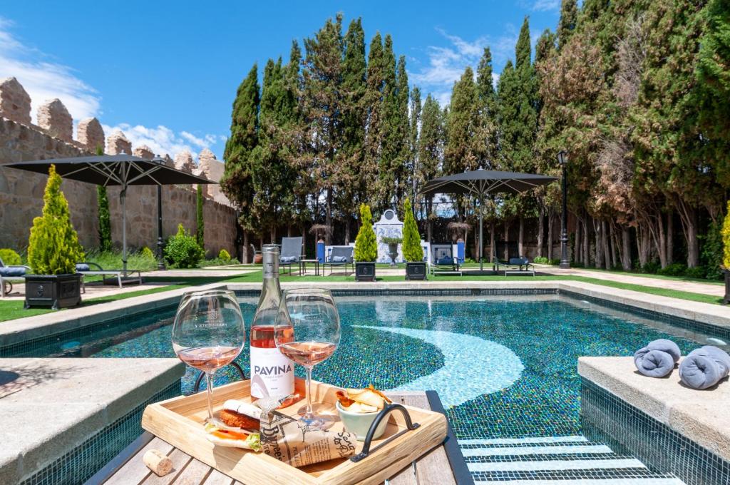 阿维拉La Casa del Presidente的一张桌子,旁边是游泳池,旁边是两杯葡萄酒