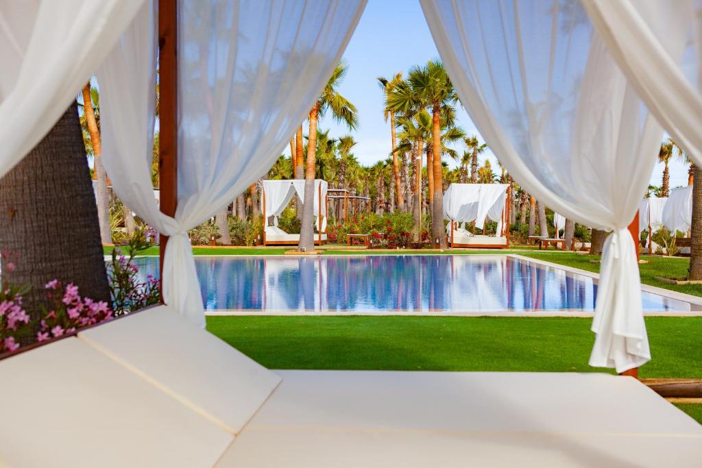 阿尔布费拉VidaMar Resort Hotel Algarve的配有床和窗帘的客房享有游泳池的景致。