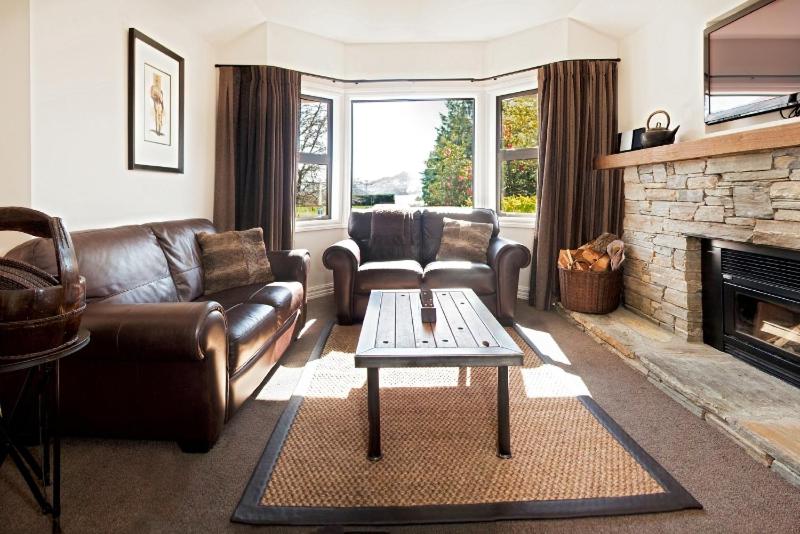 瓦纳卡Pembroke Lodge的客厅配有皮革家具和壁炉