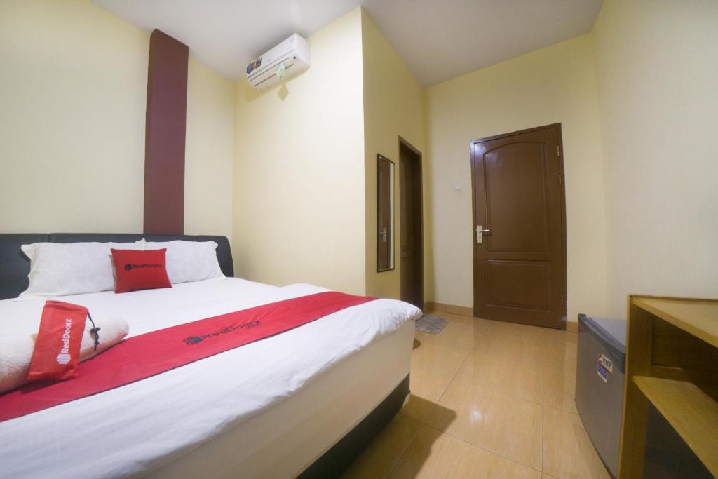 TelagaRedDoorz near TVRI Gorontalo的一间卧室配有一张带红色枕头的大床