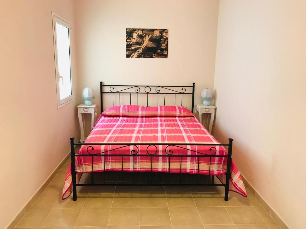 诺托玛丽娜Nilla Apartments的一间卧室配有一张带红色和粉红色毯子的床