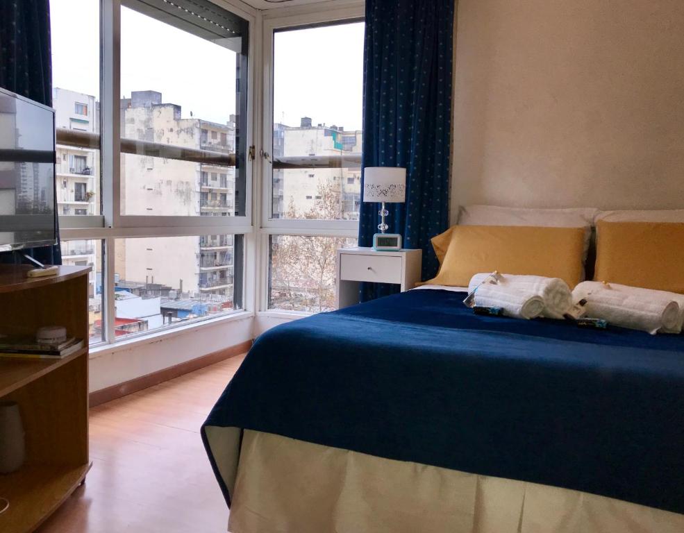 布宜诺斯艾利斯Apartamento Bulnes y Calle Corrientes的一间卧室设有蓝色的床和大窗户