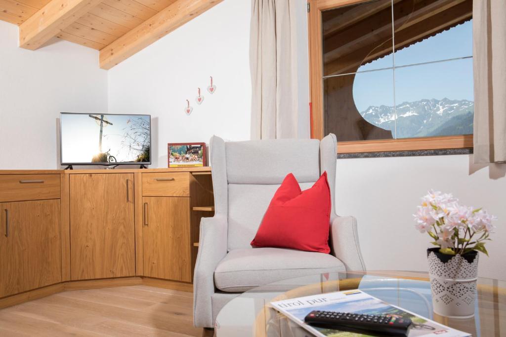 阿尔卑巴赫罗丝姆斯公寓的客厅配有红色枕头和椅子